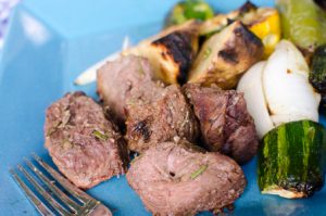 Cooked beef kebabs and grilled organic vegetables